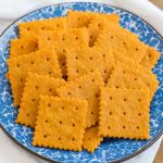 Golden crispy cheddar cheese crackers arranged on a blue speckled plate