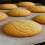 Golden soft keto almond cookies on parchment paper, freshly baked and gluten-free.