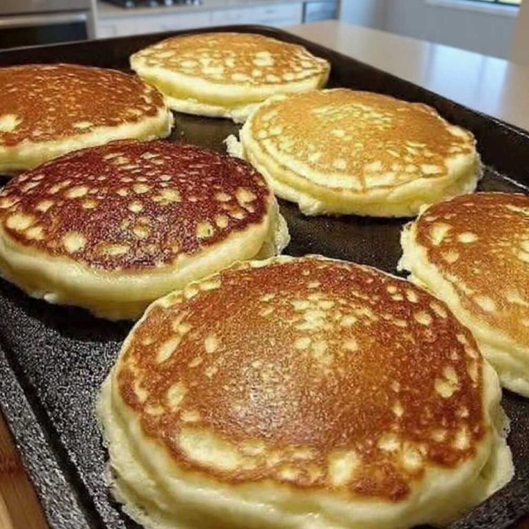Golden keto sourdough pancakes cooking on a griddle with fluffy centers