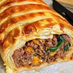 Vegan Wellington made with golden puff pastry filled with plant-based meat, spinach, and vegan cheese