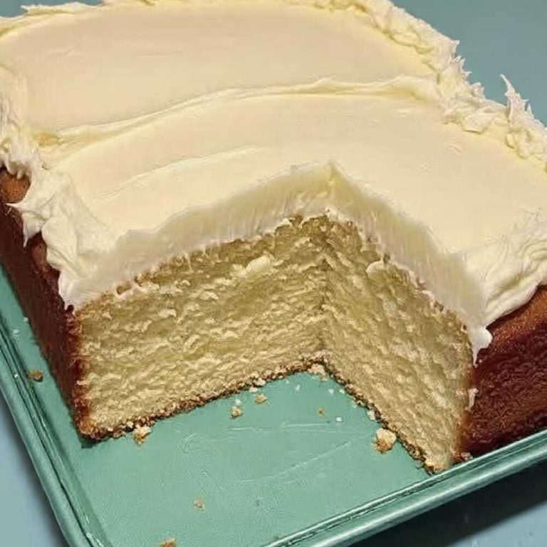 Keto lemon cake with thick creamy frosting sliced in a baking dish